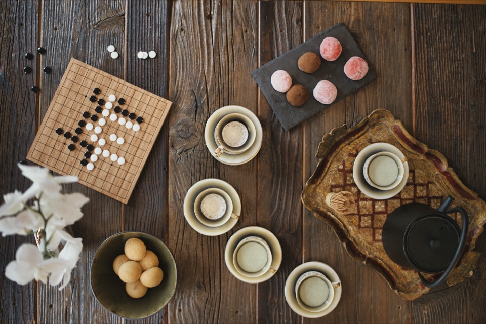 Table basse en bois avec théière en fonte, tasses, mochis et plateau de go