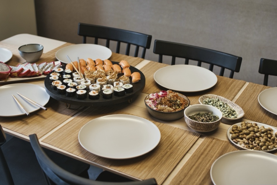 Table dressée avec plateaux de sushis, edamame et raviolis vapeur