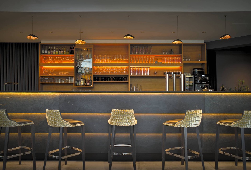 Bar d'hôtel en ardoise aux étagères rétroéclairées ambrées