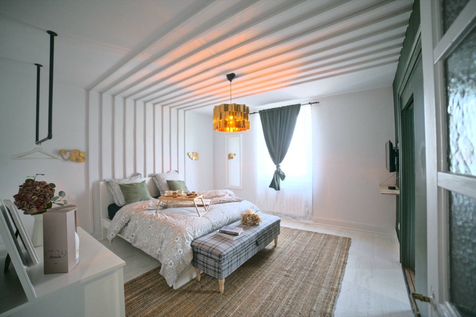 Chambre d'Airbnb au plafond à tasseaux avec plateau de petit déjeuner sur le lit