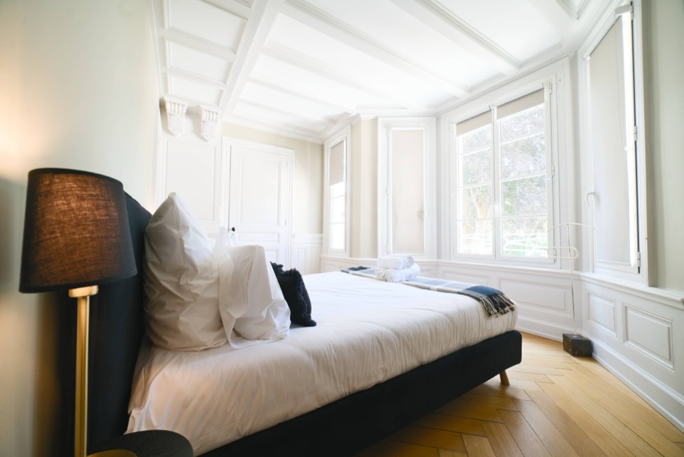 Hotel bedroom with pale wood panelling and herringbone parquet flooring