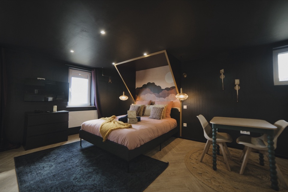 Chambre cosy aux murs sombres, fresque de nuages et linge rose poudré