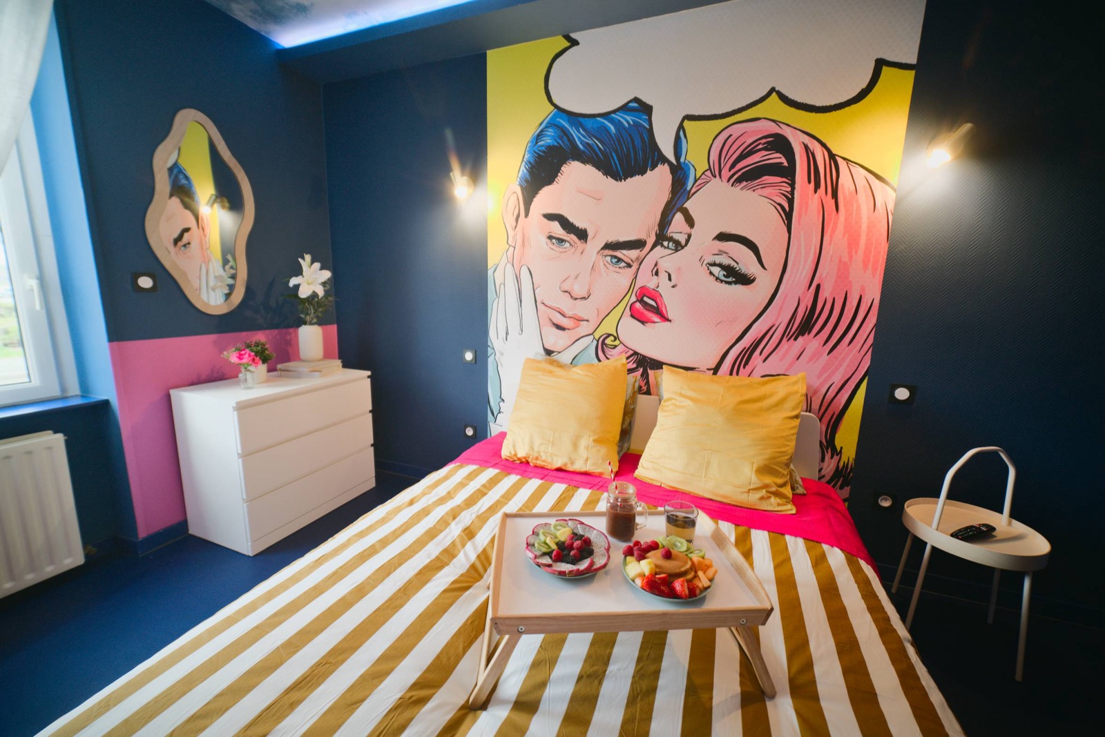 Hotel room with a bold painted wall mural behind the bed and graphic bedding