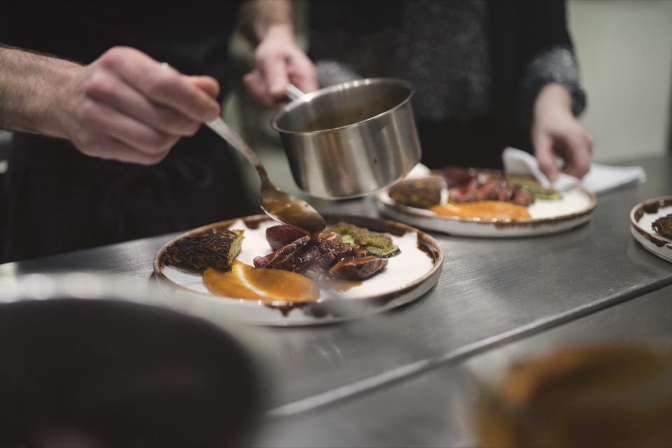 Chef nappant de sauce une assiette gastronomique au passe