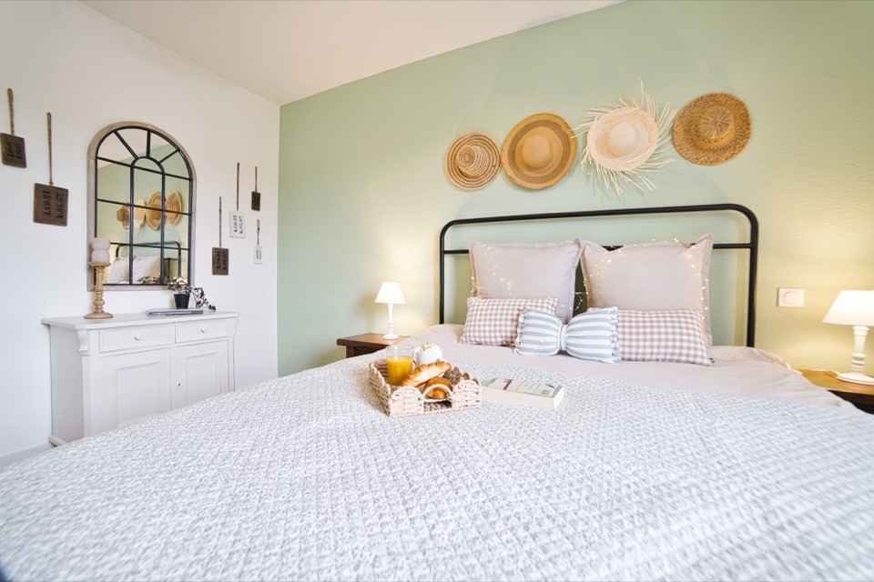 Chambre claire avec chapeaux de paille accrochés au mur et coussins vichy