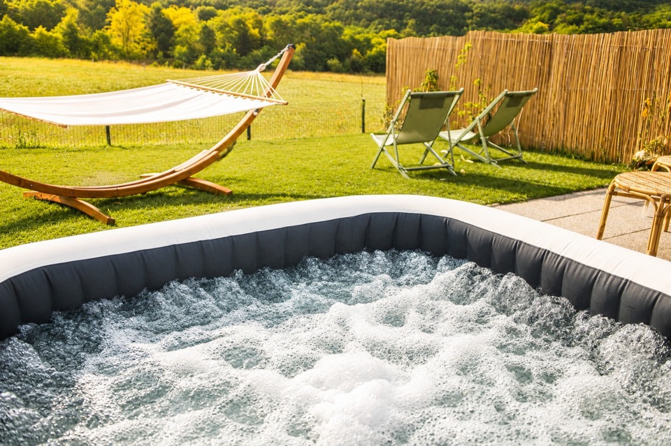 Outdoor hot tub running, hammock and meadow behind a bamboo hedge