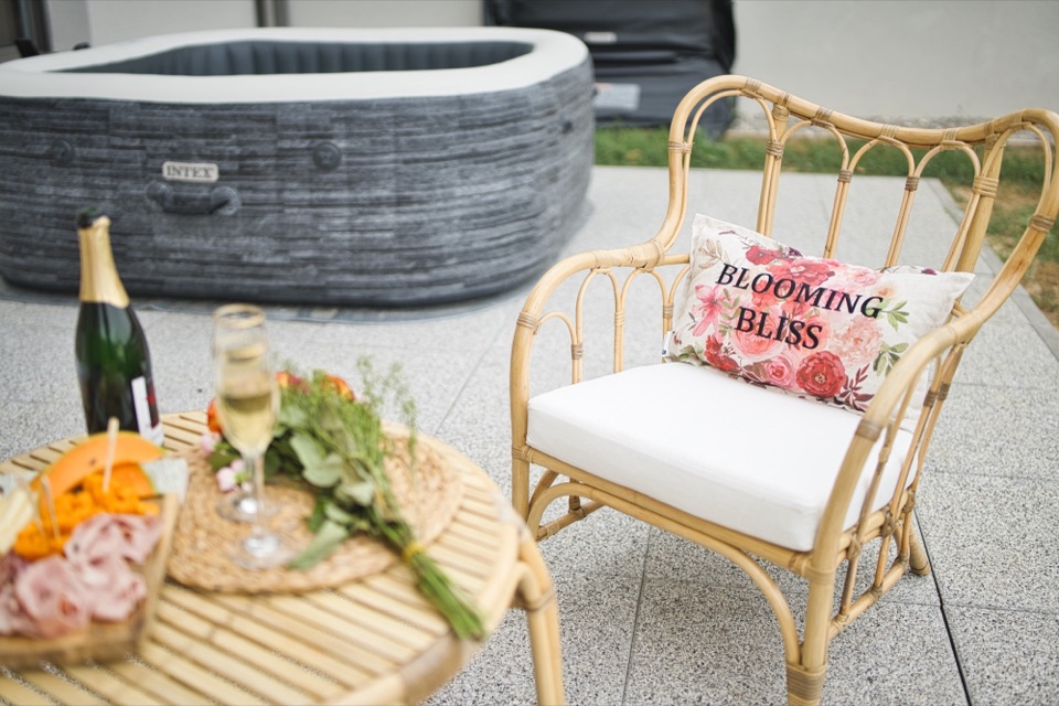 Rattan garden lounge with pink cushions and a hot tub on a terrace