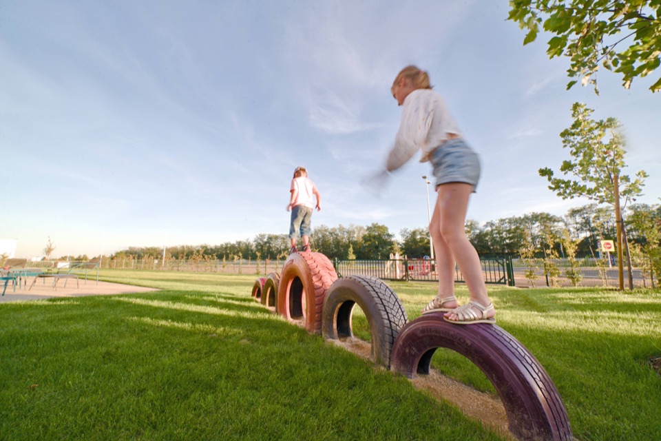 Enfants jouant sur un parcours de pneus dans le jardin d'un hôtel au soleil couchant