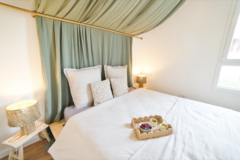 Chambre avec lit à baldaquin, voilages verts et plateau de petit déjeuner