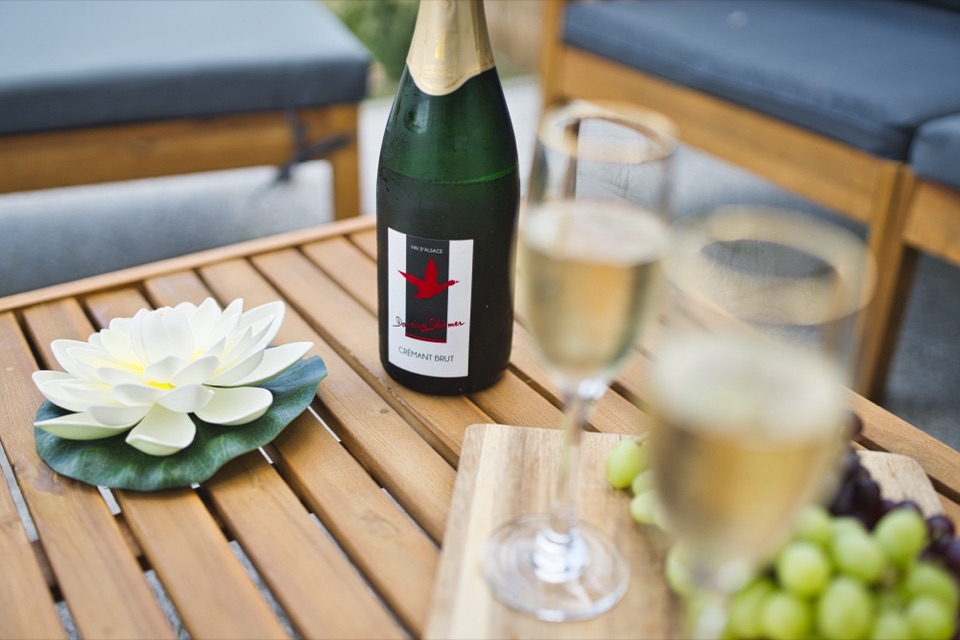 Bouteille de champagne, flûtes et fleur de lotus sur une table basse en bois en terrasse