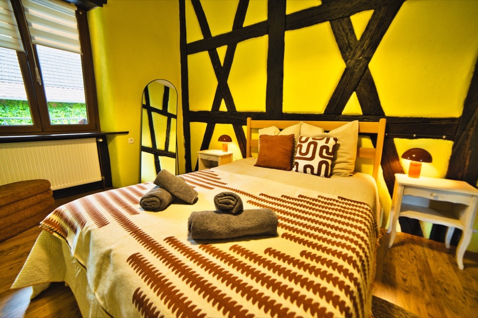 Chambre jaune à colombages avec lit double et coussins à motifs