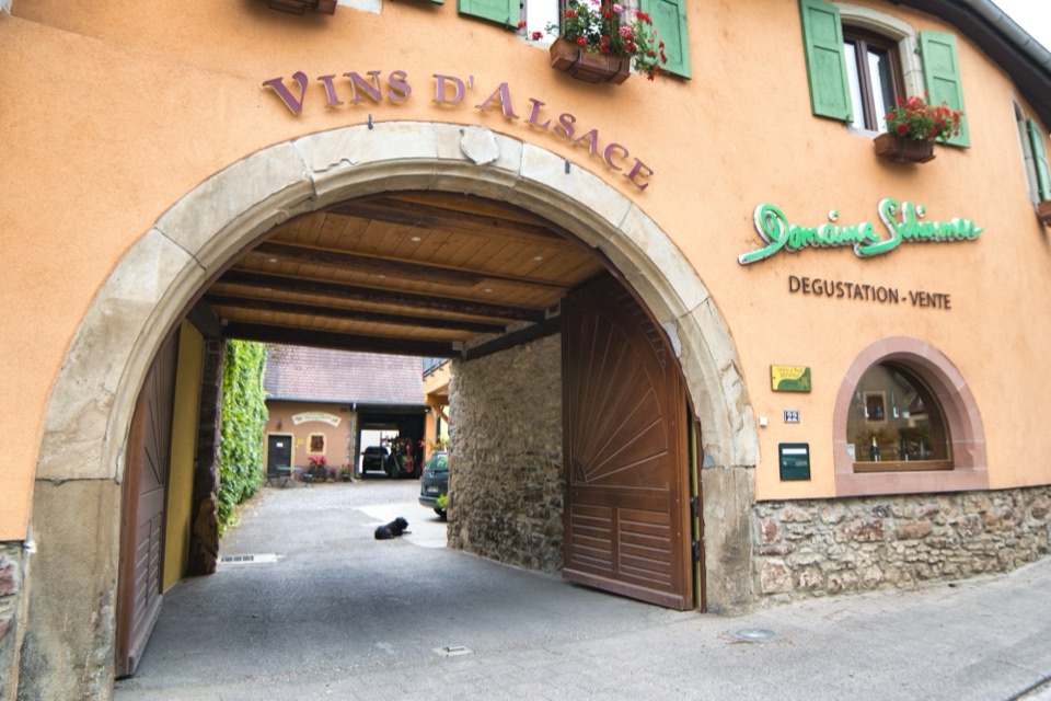 Cour intérieure d'un domaine viticole alsacien avec porche et enseigne Vins d'Alsace