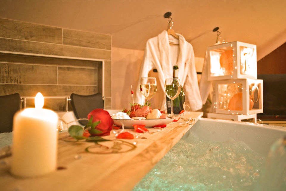 Jacuzzi romantique avec bougie, rose rouge, macarons et verres de vin