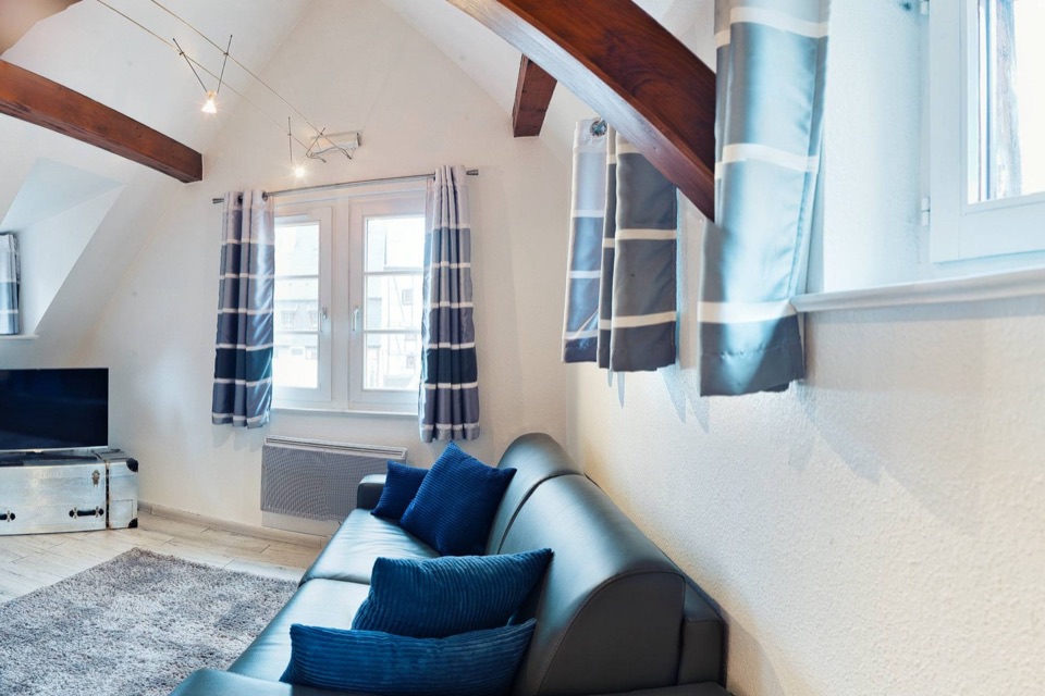 Chambre sous charpente apparente en bois, lit rond et fenêtre, extrait d'une photo 360°