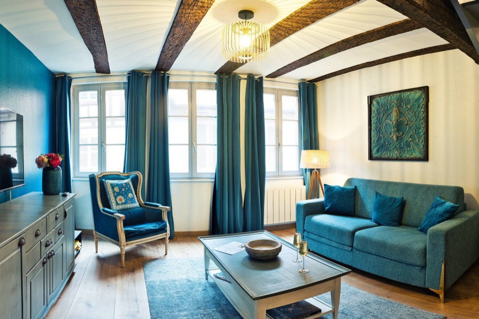 Salon bleu avec canapé, poutres et escalier en colimaçon, extrait d'une photo 360°