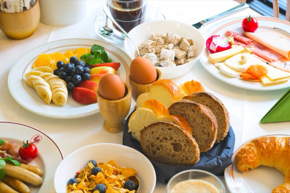 Table de petit déjeuner d'hôtel : œufs à la coque, fruits frais, brioche et café