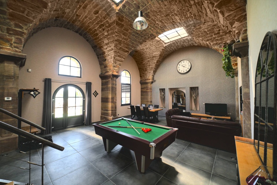 Vaste pièce à vivre sous voûtes en pierre avec billard et salle à manger, dans un gîte