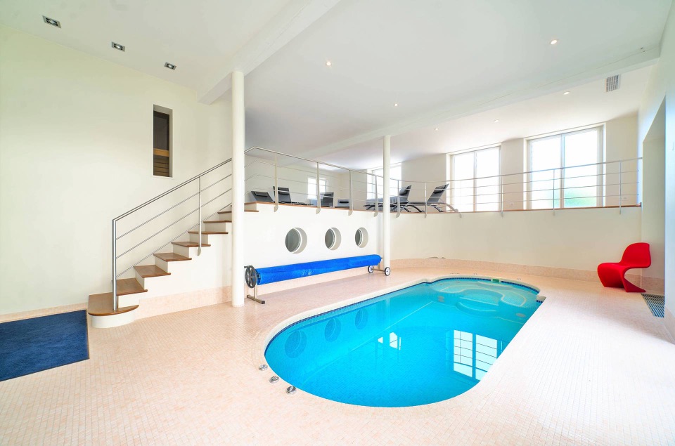 Piscine intérieure privée bordée d'une mezzanine avec transats