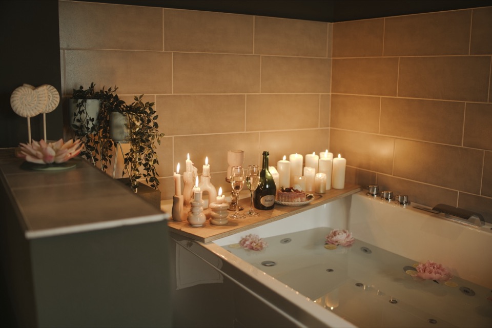 Baignoire entourée de bougies avec champagne, ambiance spa intimiste