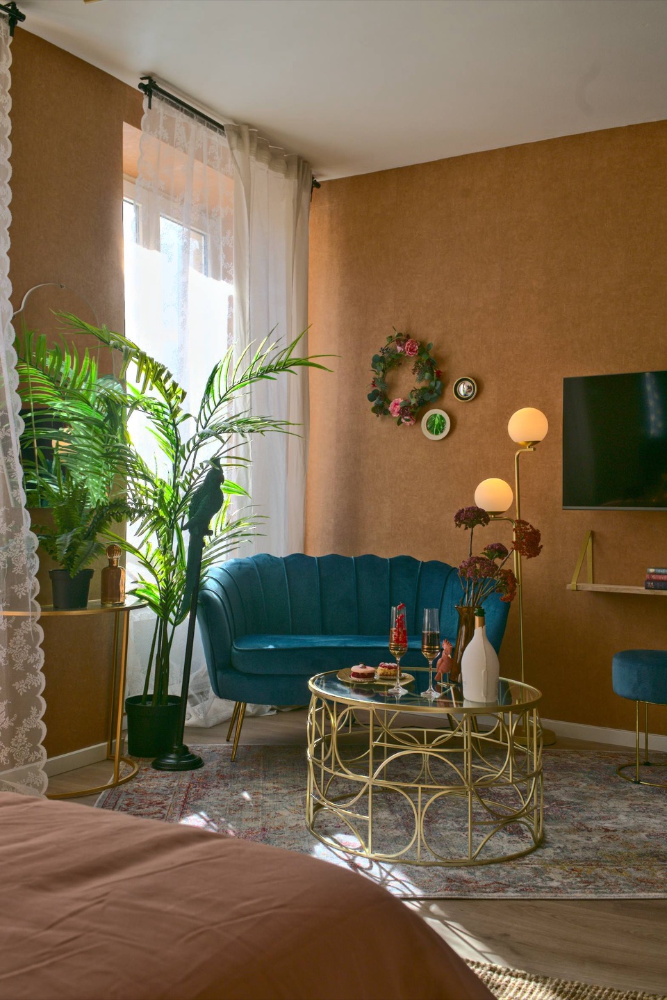 Salon bohème d'un Airbnb avec canapé coquillage en velours bleu et table dorée