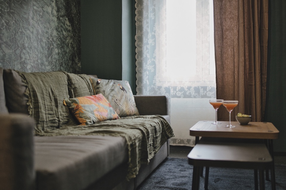 Salon cosy avec cocktails sur la table basse, dans la lumière douce de la fenêtre