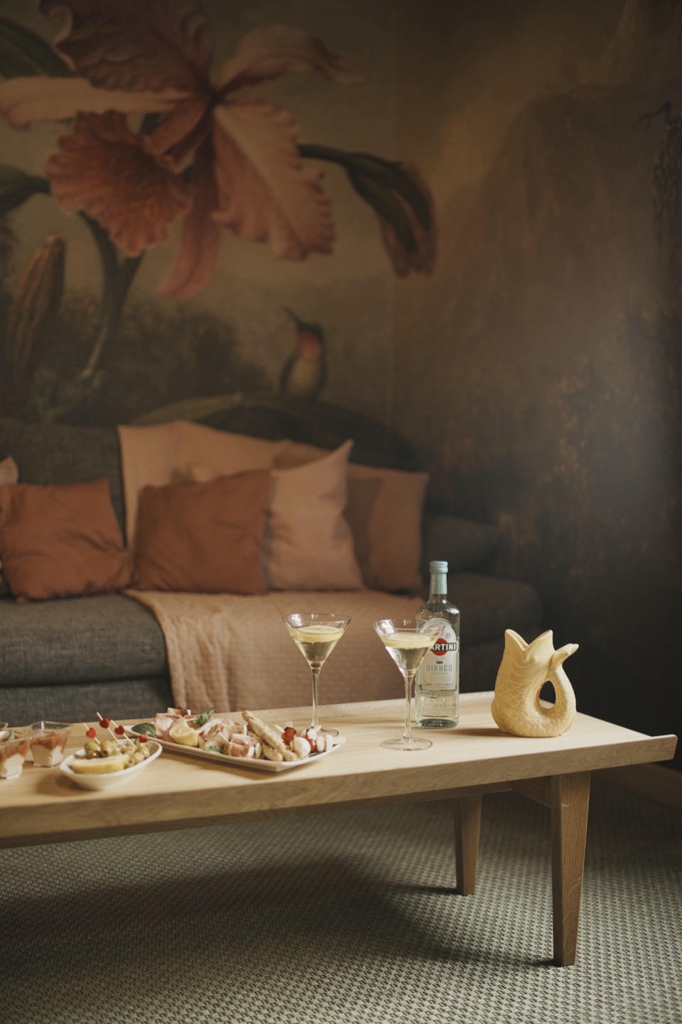 Salon de suite avec fresque murale, cocktails et plateau apéritif mis en scène