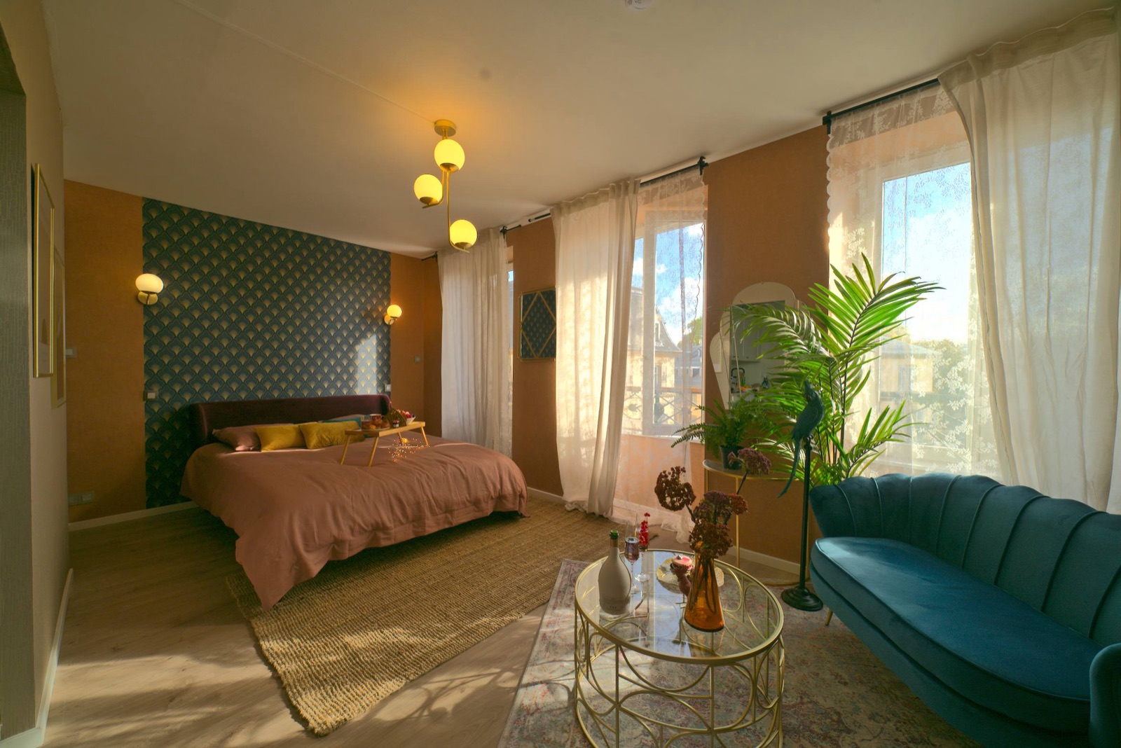 Art deco hotel suite bathed in golden light, terracotta bed and blue sofa
