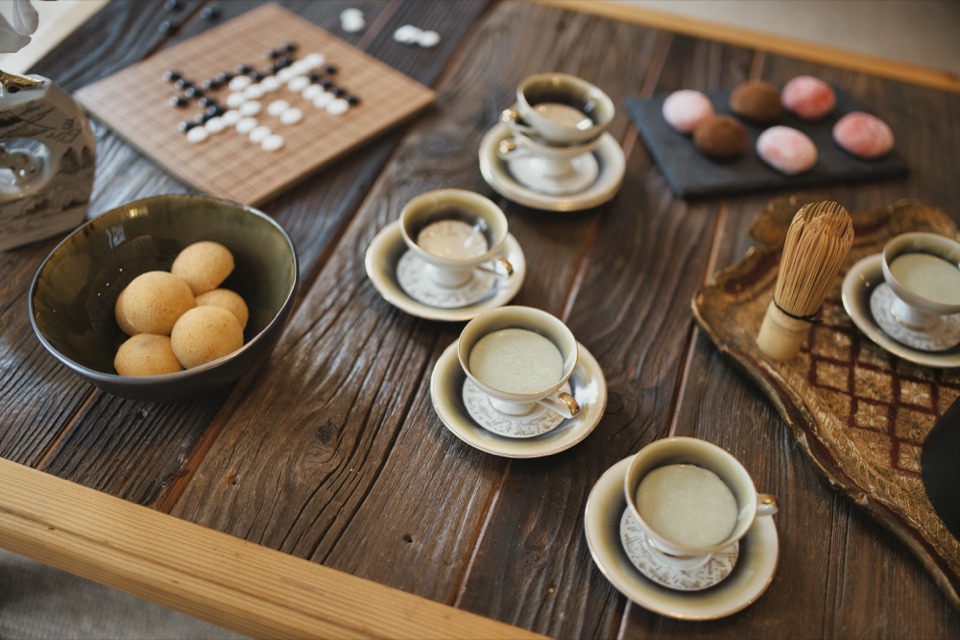 Table japonisante avec thé matcha, mochis et jeu de go sur bois brut